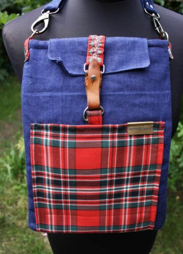 Jeansowa kopertówka z kieszenią w czerwoną kratę i vintage zapięciem na manekinie.